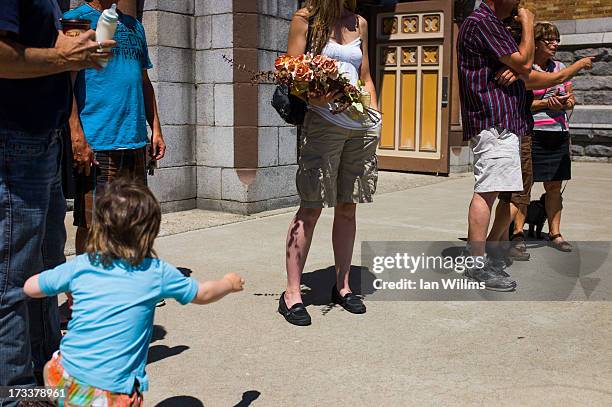 Woman brings a bouquet of flowers to a public vigil at the Presbyteres-Eglises July 12, 2013 in Lac-Megantic, Quebec, Canada. A train derailed and...