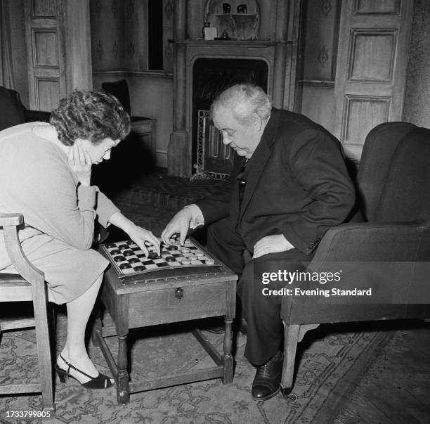 Actors Elsa Lanchester and Charles Laughton on stage playing backgammon during a performance of 'The Party' at the New Theatre, London, June 9th...