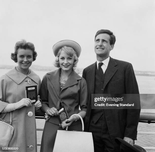 Fashion models from left: Ann Cave, Sandra Paul and Patrick Bashford standing aboard a ship holding their passports, June 10th 1958.