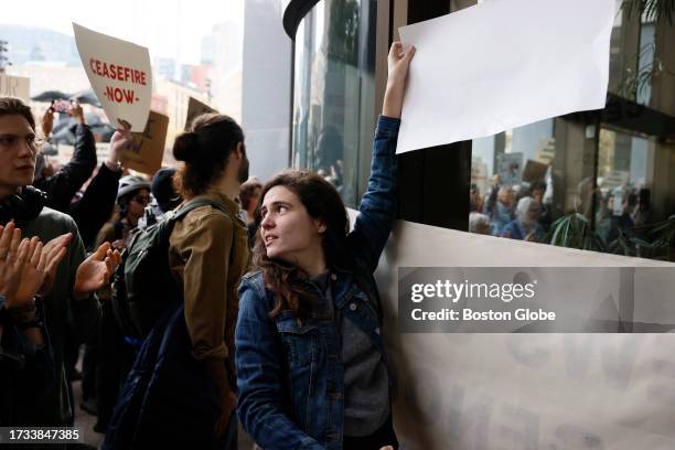 Boston, MA A protester looked back at the crowd as she pressed a sign to the window as she and others rallied outside of the John F. Kennedy Federal...