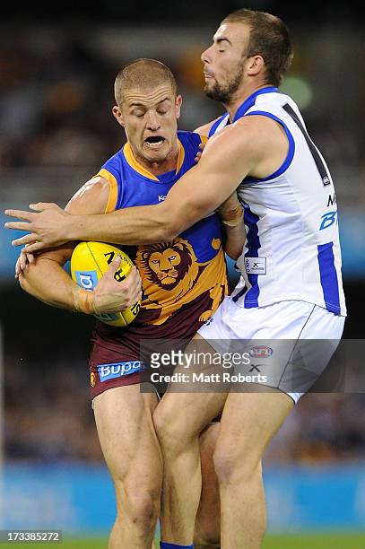 Matt Maguire of the Lions is tackled by Ben Cunnington of the kangaroos during the round 16 AFL match between the Brisbane Lions and the North...