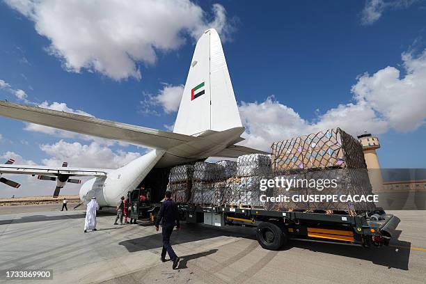 Staff members unload aid for the Palestinian Gaza Strip from an Emirates cargo plane on the tarmac of Egypt's el-Arish airport in the north Sinai...