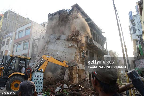 An Indian worker uses a bulldozer to demolish shops and houses near the Jallianwala Bagh in Amritsar on July 13, 2013. The buildings and shops were...