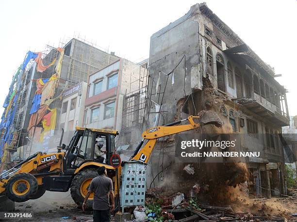 An Indian worker uses a bulldozer to demolish shops and houses near the Jallianwala Bagh in Amritsar on July 13, 2013. The buildings and shops were...