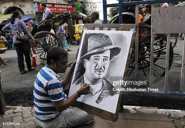 Street painter Ramjan Hussain giving the finishing touch on the portrait of Bollywood villain actor Pran at Esplanade on July 13, 2013 Kolkata,...