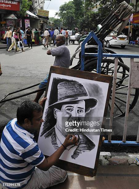 Street painter Ramjan Hussain giving the finishing touch on the portrait of Bollywood villain actor Pran at Esplanade on July 13, 2013 Kolkata,...