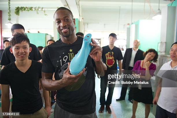 Dwyane Wade holds up his foot mould for his "Way of Wade" shoes while touring the Li-Ning shoe manufacturing factory on July 12, 2013 in Tai Cang,...