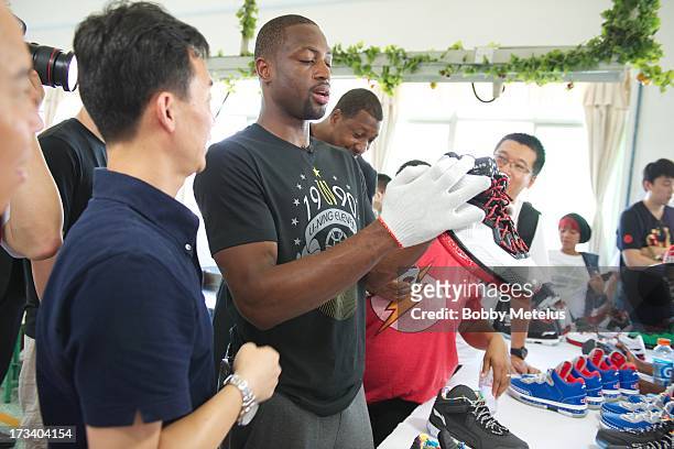 Dwyane Wade inspects a new batch of "Way of Wade" shoes for quality control at the Li-Ning shoe manucaturing factory on July 12, 2013 in Tai Cang,...