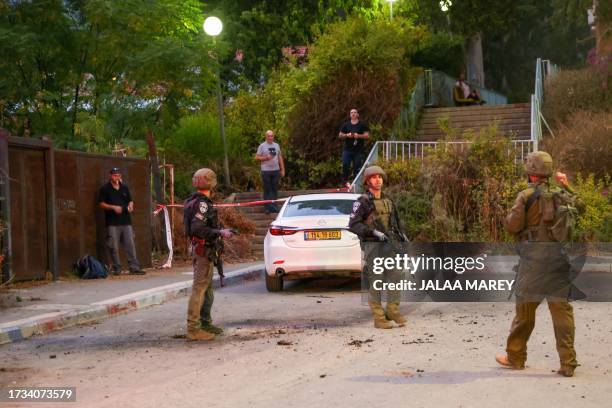 Israeli security forces inspect a site where a rocket launched from Lebanon fell in the northern city of Kiryat Shmona near the border on October 19...