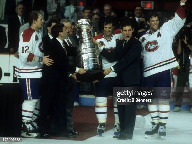 Commissioner Gary Bettman presents the Stanley Cup Trophy to Denis Savard, Guy Carbonneau, Kirk Muller and Mike Keane of the Montreal Canadiens after...