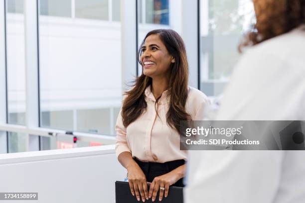 female hospital administrator smiles while listening to her unseen coworker - administrative professionals stockfoto's en -beelden