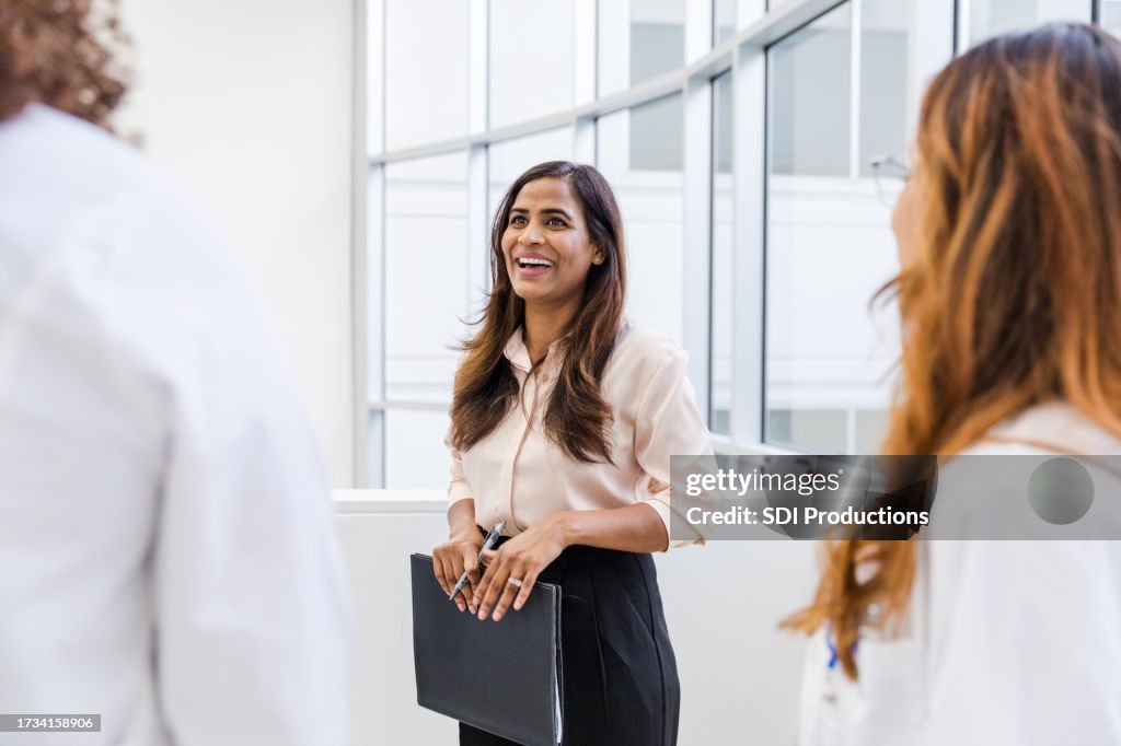 Mid adult female social worker smiles while talking with her colleagues