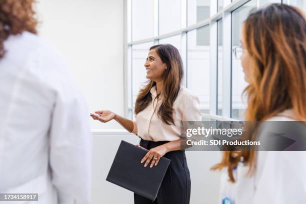 businesswoman smiles and talks with the unrecognizable healthcare professionals - medical director stock pictures, royalty-free photos & images