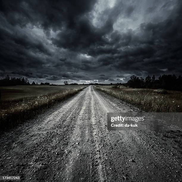country road in a field at storm - landweg stockfoto's en -beelden