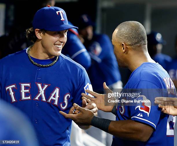 Derek Holland of the Texas Rangers smiles while talking with Adrian Beltre after pitching in the seventh inning of a game against the Detroit Tigers...