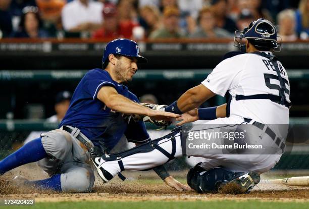 Ian Kinsler of the Texas Rangers avoids the tag from catcher Brayan Pena of the Detroit Tigers to score from second base on an infield single in the...