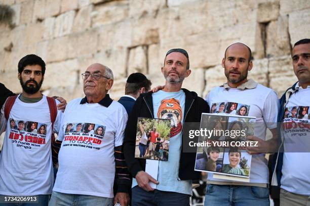 Relatives of missing Israelis lift portraits of their loved ones in front of the Western Wall while attending a day of prayer in the Old City of...