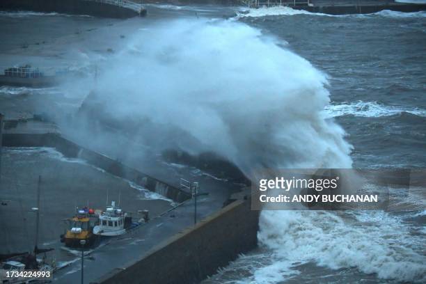 Waves crash over Stonehaven harbour on the east coast of Scotland on October 19 as wind and rain from Storm Babet cause travel chaos.