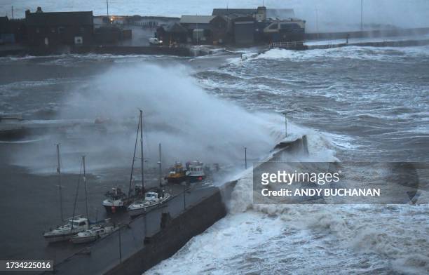 Waves crash over Stonehaven harbour on the east coast of Scotland on October 19, 2023 as wind and rain from Storm Babet causes travel chaos.
