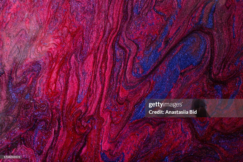 Liquid abstract background from red and blue shimmer nail polish. Good for text overlay.