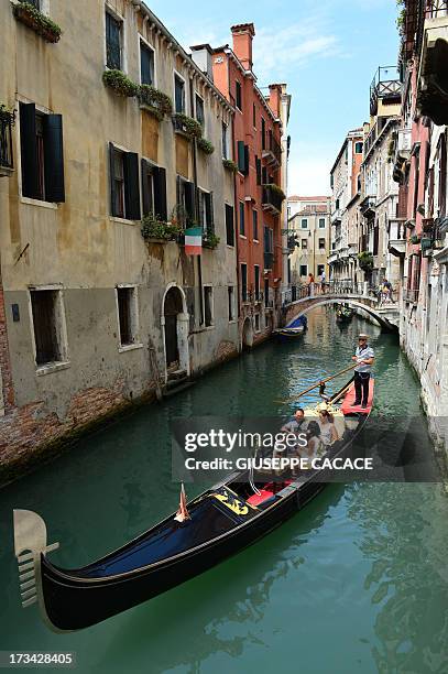 Picture taken on July 10, 2013 shows tourists enjoying a gondala ride near Piazza San Marco in Venice. AFP PHOTO / GIUSEPPE CACACE