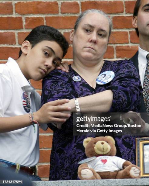 Mark Sanchez who lost his dad, Jesus Sanchez, holds the hand of Lynn Greene of East Boston as they remember United Airlines co-workers Sanchez and...