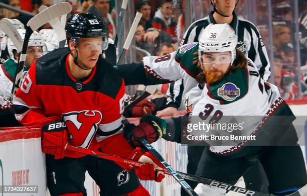 Liam O'Brien of the Arizona Coyotes checks Jesper Bratt of the New Jersey Devils during the first period at Prudential Center on October 13, 2023 in...