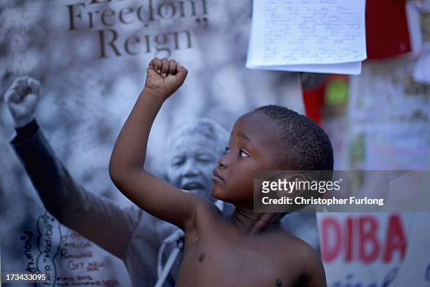 Young boy, a member of the Maitibolo Cultural Dance Troop, pays his respects to Former South African President Nelson Mandela at the tribute wall...