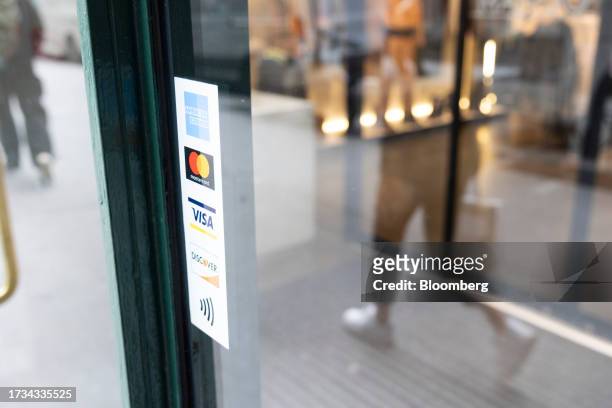 Sticker for American Express, Mastercard, Visa and Discover credit cards displayed on a street cart in New York, US, on Tuesday, Oct. 17, 2023....