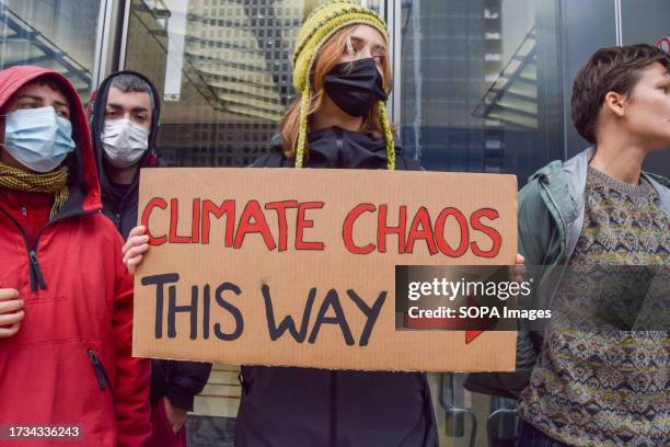 Protester holds a placard which states 'Climate chaos this way' during the demonstration outside JP Morgan. The climate activists, joined by Greta...