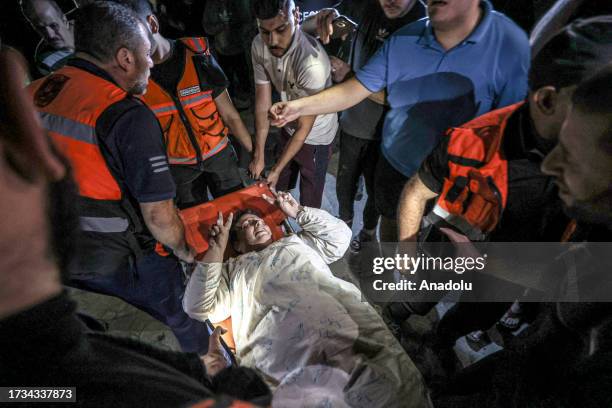 Personnel carry an injured civilian at the scene of destruction after an Israeli attack on the Greek Orthodox Church in Gaza City, Gaza on October...