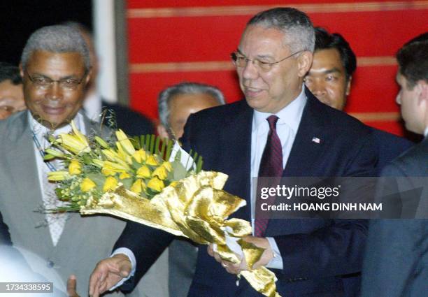 Secretary of State Colin Powell holds a bunch of flowers as he is greeted upon his arrival 17 June 2003 at Phnom Penh's Pochentong airport. On his...