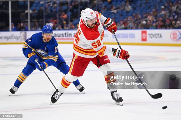 MacKenzie Weegar of the Calgary Flames shoots the puck as Tyson Jost of the Buffalo Sabres defends during an NHL game on October 19, 2023 at KeyBank...