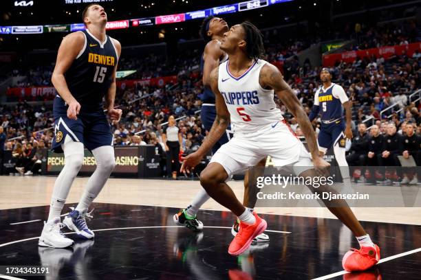 Bones Hyland of the Los Angeles Clippers turns his left ankle on landing after going up for a basket against Peyton Watson and Nikola Jokic of the...