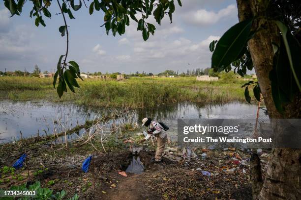 Helena Ubisse, who works with Goodbye Malaria, drops mosquito larvicide into pools a standing water where there was a road before major flooding...