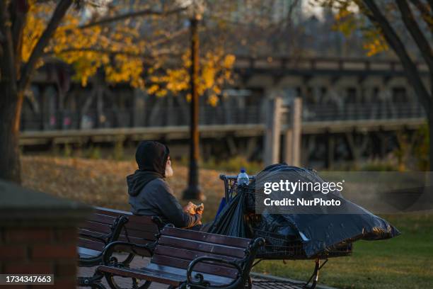 Homeless person sitting inside Constable Ezio Faraone Park during a sunset, on October 11 in Edmonton, Alberta, Canada.