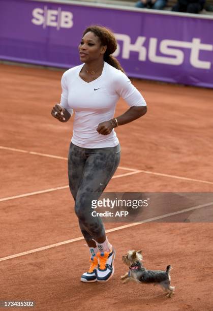 Tennis player Serena Williams warms up next to her Yorkshire terrier "Chip" during a training session, prior to her participation in the Swedish Open...