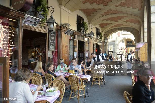 Photo taken on July 12, 2013 shows people on the terrace of a cafe under the arcades of the Place des Vosges in the Marais district in the 3rd and...