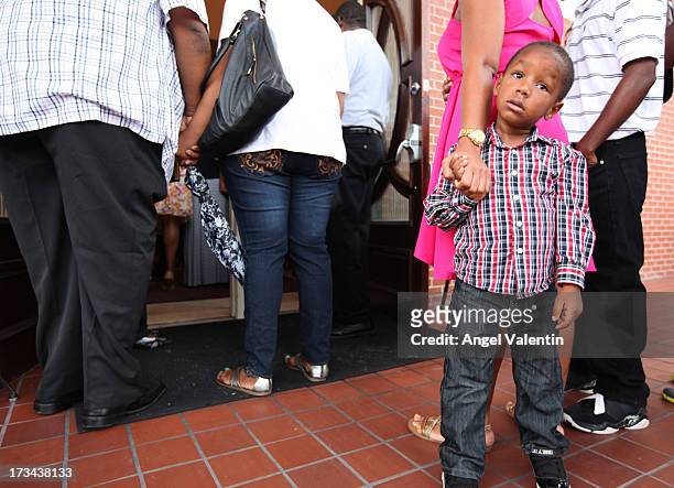 Chad Collins holds on to his mother's hand while church goers pray at the entrance of the Antioch Missionary Baptist Church a day after the verdict...