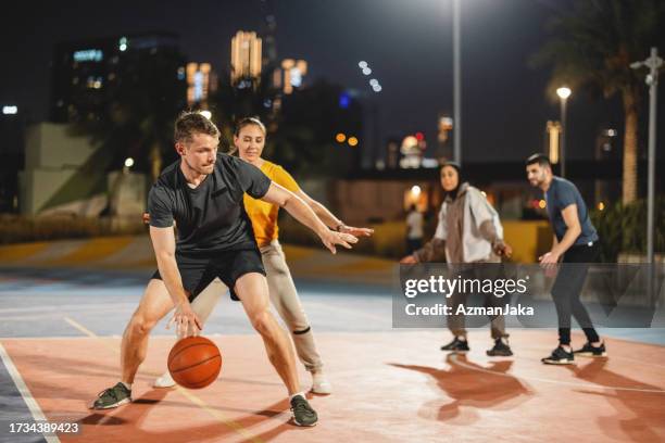 a group friends playing basketball  after work at night in dubai - game 27 23 stock pictures, royalty-free photos & images