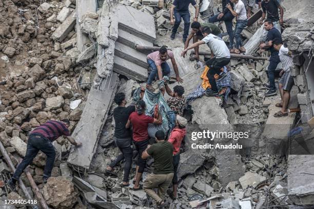 People carry a dead body pulled from rubble as civil defense teams and residents continue search and rescue efforts in the historical Greek Orthodox...