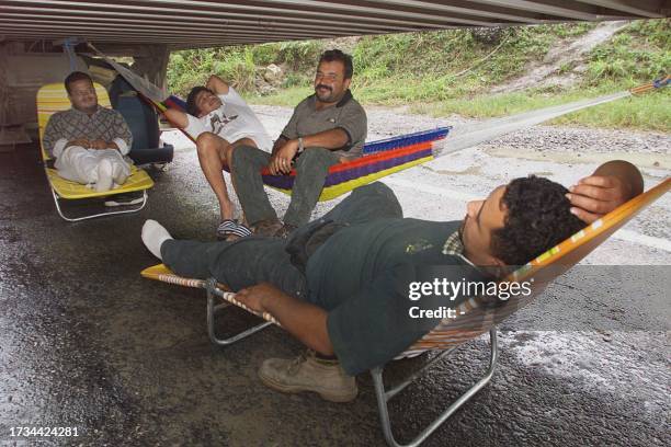 Group of Guatemalean citizens originating from the US in transit in Papantla, Mexico pass the day under a tractor trailer 14 October, 1999. Many of...