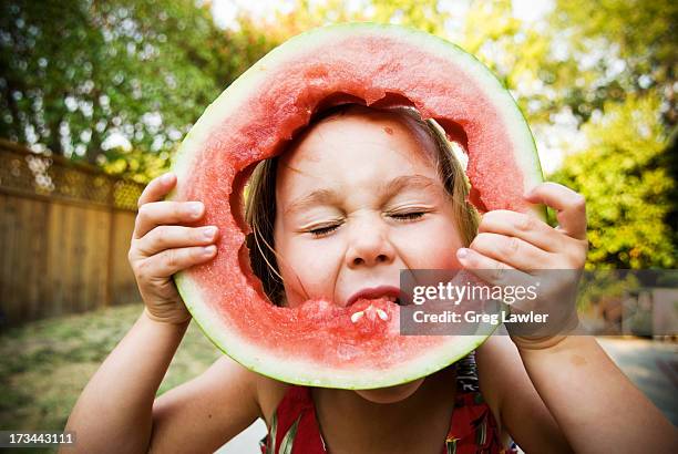 a young girl blissfully eating watermelon - children fruit stock-fotos und bilder