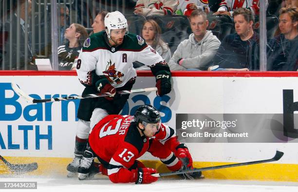 Nick Schmaltz of the Arizona Coyotes checks Nico Hischier of the New Jersey Devils during the second period at Prudential Center on October 13, 2023...