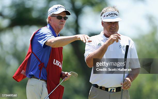 Kenny Perry chats with his caddiie Freddie Sanders on the second green during the final round of the 2013 U.S. Senior Open Championship at Omaha...