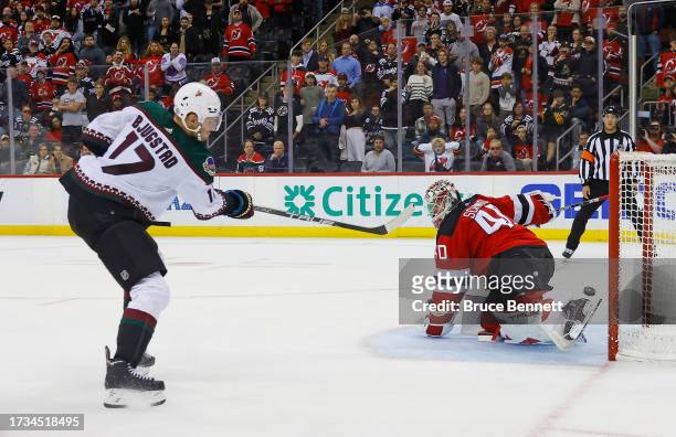 Nick Bjugstad of the Arizona Coyotes scores in the shootout against Akira Schmid of the New Jersey Devils at Prudential Center on October 13, 2023 in...