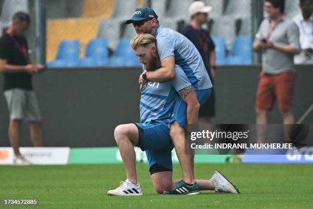 England's Ben Stokes is assisted by a team member during a training session at the Wankhede stadium in Mumbai on October 20, 2023 ahead of their 2023...