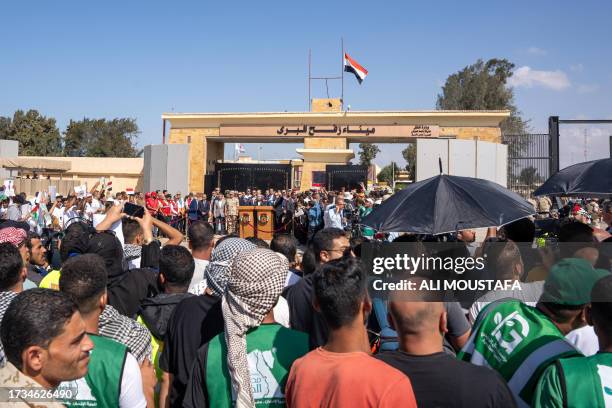 Pro-Palestinian protesters listen as UN Secretary-General Antonio Guterres gives a press conference on the Egyptian side of the Rafah crossing on the...