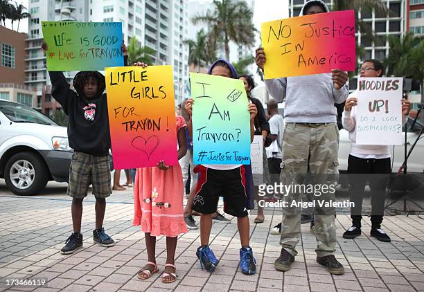 Demonstrators hold signs in front of the Torch of Friendship in downtown Miami a day after the verdict to the George Zimmerman murder trail on July...