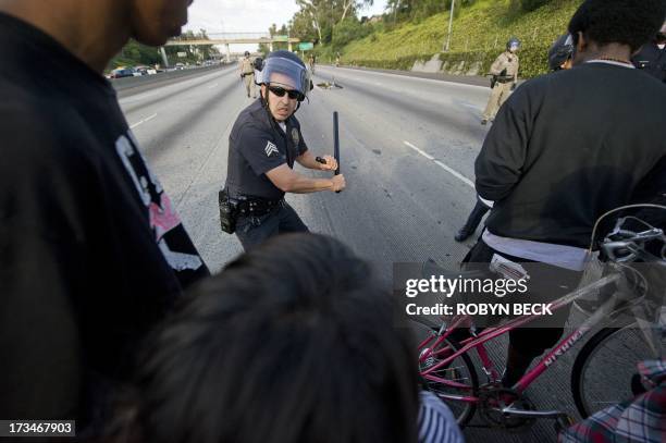Police officer takes a defensive stance as he and colleagues hold a line stopping protestors from advancing on the 10 Freeway after demonstrators...